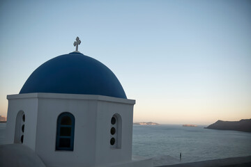 Fototapeta na wymiar The top of a picturesque Greek Orthodox Church overlooking the Aegean Sea in Oia Santorini