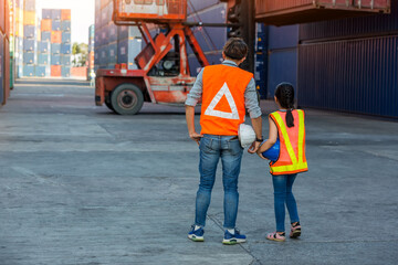 Father and little daughter wearing a safety helmet at Container cargo site. Business heir concept. Happy father and daughter wearing safety helmet work site. Business heir concept.	