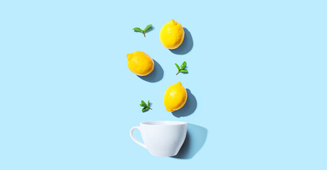 Obraz na płótnie Canvas Fresh yellow lemons with tea cup overhead view - flat lay