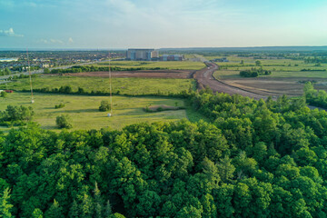 Aerial shot of Hospital in the background with dirt road construction in the middle ground and beautiful forest in the foreground