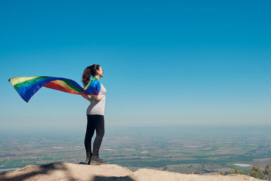 Young Hiker On Mountaintop With Gay Pride Flag As Cape