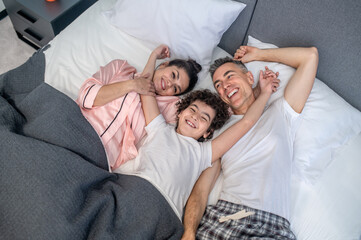 A cute family staying in bed smiling and looking cheeful