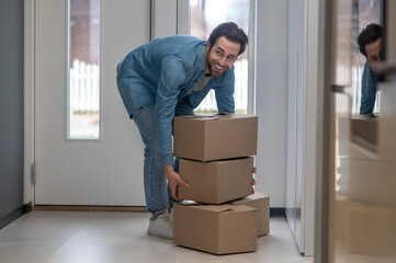 Man bending over with boxes smiling to side