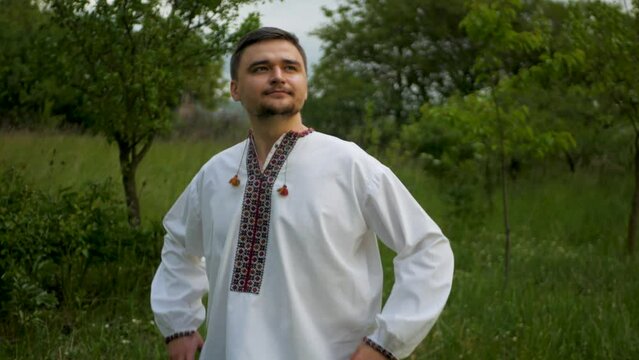 Adult white male in traditional Ukrainian national outfit inhaling deeply and embracing nature. Caucasian man in beautiful embroidered vyshyvanka taking a deep breath and knowing everything will be ok
