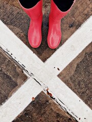 X marks the spot, person in pink rain boots standing on pavement