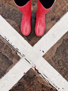 X marks the spot, person in pink rain boots standing on pavement
