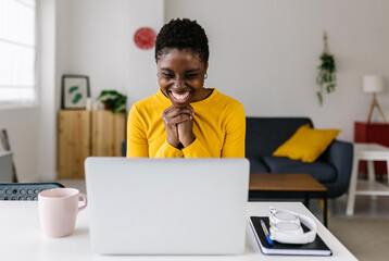 Excited young african woman celebrating success looking at laptop screen - Millennial female...