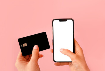 Hands holding credit card and phone on pink background. Online shopping, Valentines Day romantic...