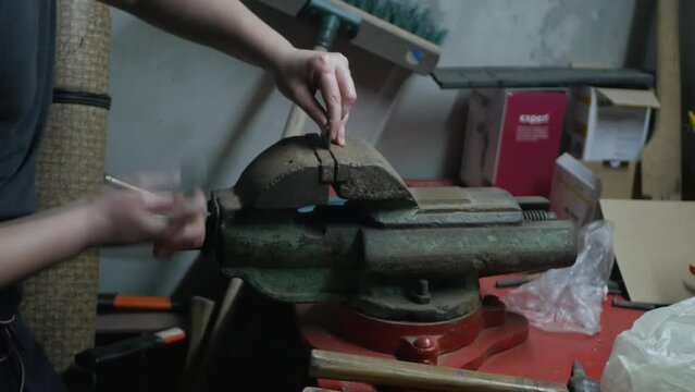 Male caucasian hands working on pressure machine on small metal part. Close up of man laborer using industrial machinery on worktable. Local mechanic working in small garage on broken car parts
