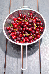 heap of fresh cherries in metal strainer