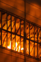 The glass and iron facade of huge skyscraper at sunset, steel, orange color, reflection of sun
