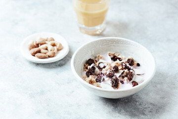 Bowl of granola with yogurt, nuts, cranberry and cocoanut. Concept for a tasty and healthy meal. Stone background.