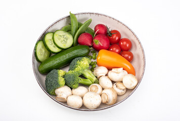 A composition of spring vegetables on a plate, isolated. Colorful veggies, top view, banner with a copy space 