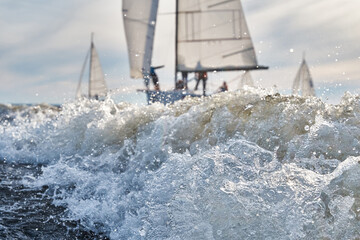 Sailing yachts in regatta at sunset, sailing regatta, hot pursuit, splashes of water, the clear sky 
