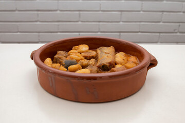 A terracotta plate with Asturian fabada, a typical Spanish bean stew, on a white background. Spanish food concept.