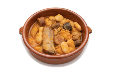 A terracotta plate with Asturian fabada, a typical Spanish bean stew, on a white background. Spanish food concept.