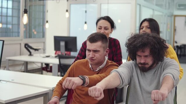 Multiethnics startup business team of software developers having fun while racing on office chairs,excited diverse employees laughing enjoying funny activity at work break