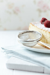 Measuring scoop with powder sugar and Piece of cheese cake. Close up.