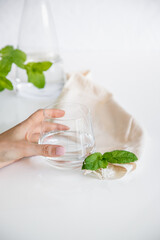 Person taking a glass of water. Glass cup containing natural water on white background. Minimalist image. Drinking water simplicity concept.