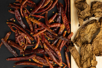Chiles rojos sobre fondo negro con tabla de madera.