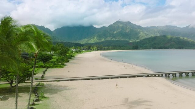 Aerial Kauai Hawaii USA tourism drone footage concept. Hanalei Beach Pier with green jungle mountains on cinematic background. Epic green nature landscape view on sunny summer day, 4K travel footage