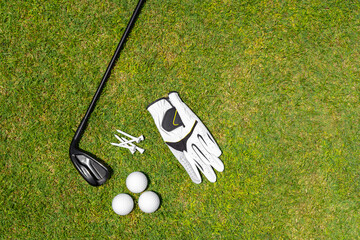 Top view of golf equipment on green grass on a golf course. Flat lay of golf club, balls, glove,...