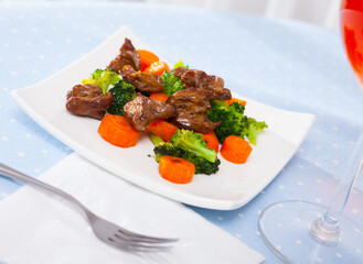 Appetizing braised chicken hearts with vegetable garnish of steamed broccoli and carrots..