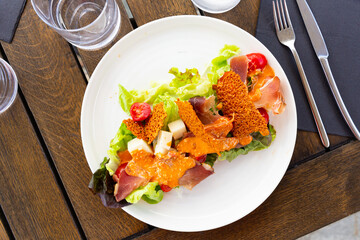 Delicious French Basque salad with cheese, cured ham, greens and cherry tomatoes