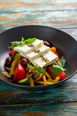 Greek salad with feta and vegetables on green wooden table vertical
