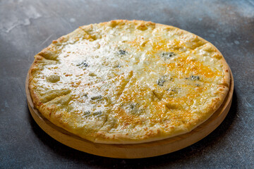 Pizza Quattro formaggi on the board on dark blue stone table
