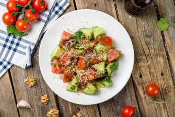 vegetable salad with tomatoes, cucumbers and walnuts top view on wooden table georgian kitchen