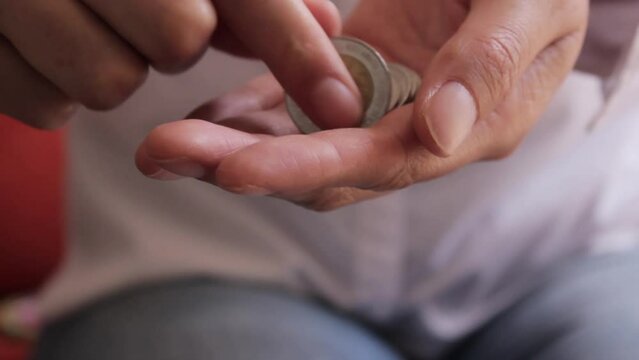 Manos de persona contando monedas mexicanas