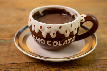 Caneca de chocolate quente isolado em fundo de mesa rústica.