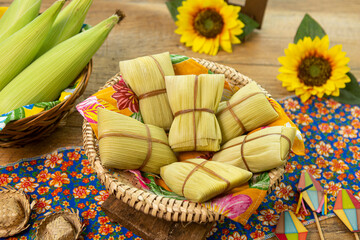 Pamonhas feitas de milho verde cozidas e embrulhadas em palha de milho. Em fundo de mesa decorada. Imagem com foco seletivo. Tradicional prato brasileiro para festa junina.