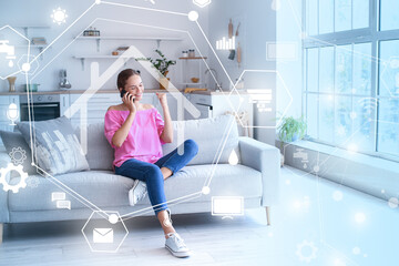 Happy young woman talking by mobile phone on sofa at home. Modern technology and smart home automation