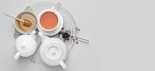 Teapots, cup of tea and honey on light background with space for text