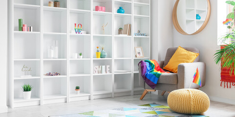 Interior of modern living room with armchair, shelving unit and LGBT flags