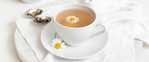 Cup of chamomile tea on light background