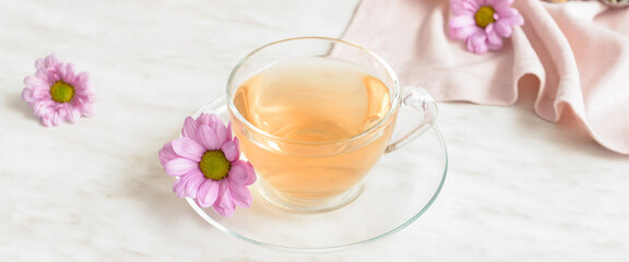 Cup of tea and fresh flowers on light background