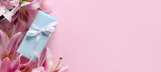 Beautiful lilies and gift box on pink background with space for text