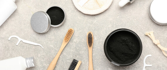 Composition with activated charcoal powder, toothbrushes and floss toothpicks on grey background,...