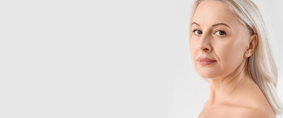 Beautiful mature woman on light background with space for text. Concept of ageing and menopause