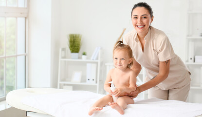 Massage therapist with cute baby in medical center - obrazy, fototapety, plakaty