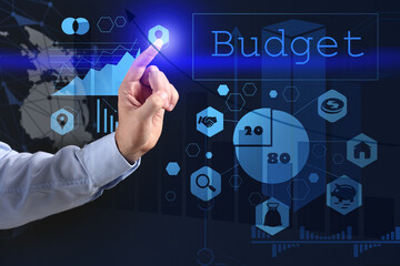 Businessman pointing at word BUDGET on virtual screen against dark background, closeup