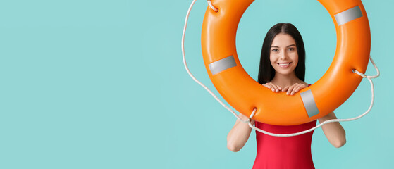 Female beach rescuer holding lifebuoy on light blue background with space for text