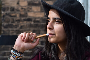Closeup portrait young girl in black hat holding vaping e cigarette