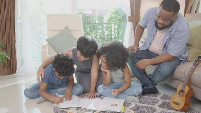 Happiness family with father and mother looking children drawing with colorful pencils and encouragement together in the living room at home, activity and hobby for learning, education concept.