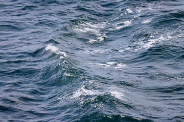 Waves far in open Baltic sea. Deep blue water, white foam on top of waves. Photo taken from ship