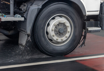Fototapeta na wymiar Detail of the wheel of a truck driving in the rain on a wet road.