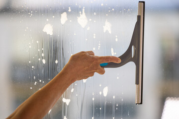 A woman cleans windows with a squeegee.